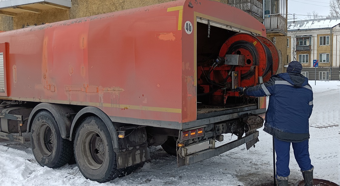 Каналопромывочная машина и работник прочищают засор в канализационной системе в Марксе